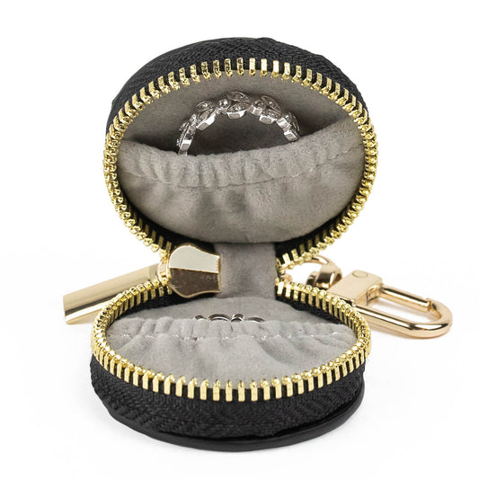 The Ring Keeper (isolated on white background) shown in Black & Gold version. Product is unzipped to reveal grey fabric lining with two inner pockets – each stashing a diamond ring.